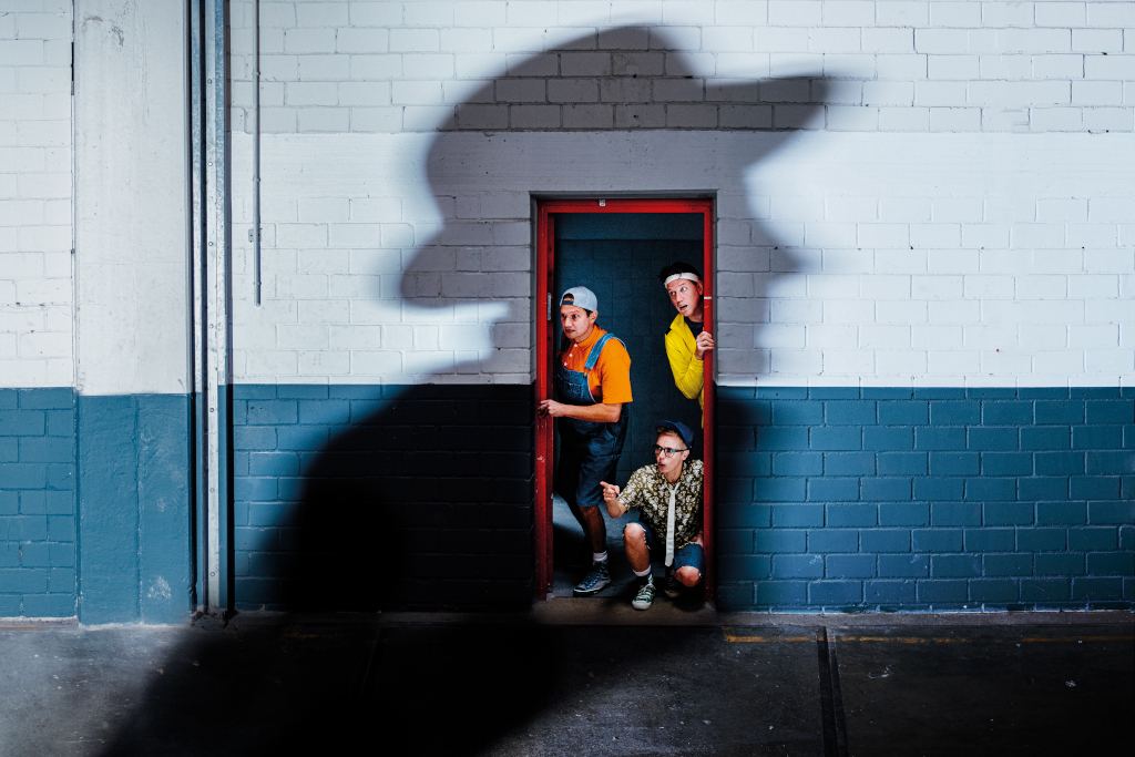 Justus, Peter und Bob schauen durch eine Tür, auf die ein mysteriöser Schatten fällt. (c) Norman Tebel