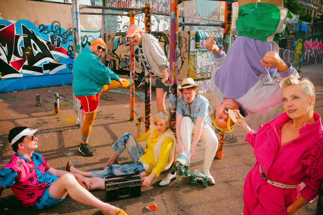 Das VPT-Ensemble in 80er-Klamotten auf'm Spielplatz. Einer hängt kopfüber und wird mit einer Banane gefüttert. Foto: Norman Tebel